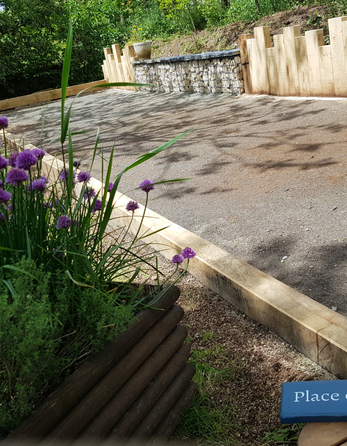 Aménagement d’un terrain de pétanque avec bordures bois et soutènement paysager réalisé par Jardins du Moulin